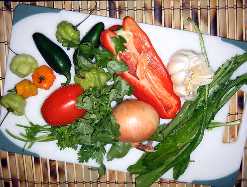 Ajíes dulces, jalapeños, bell pepper, onion, garlic, tomato, cilantro, and recao on a white board